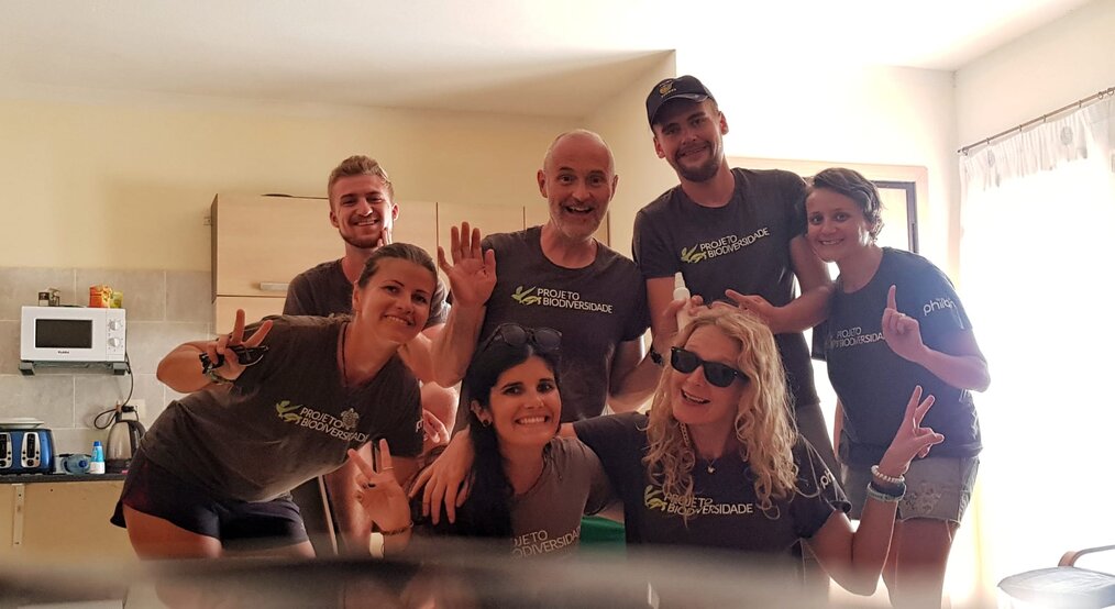 A group of volunteers smile and wave at the camera.